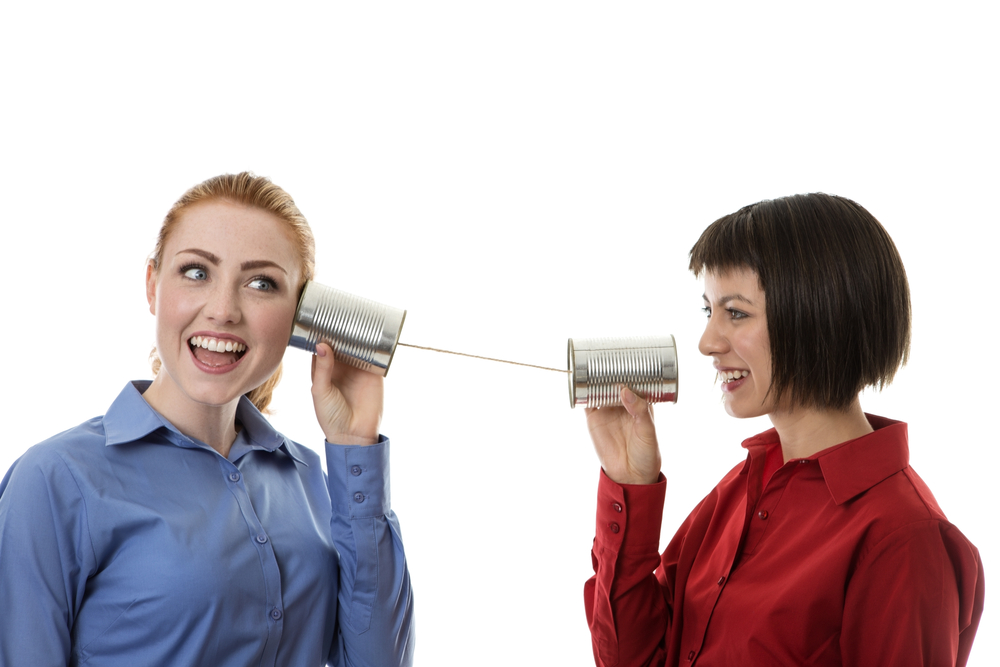 Two women talking with tin cans to symbolize communication difficulties