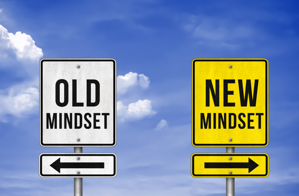 two signs pointing in opposite directions saying Old Mindset and New Mindset